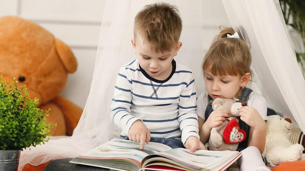 Kinder sitzen nebeneinander und betrachten ein Buch